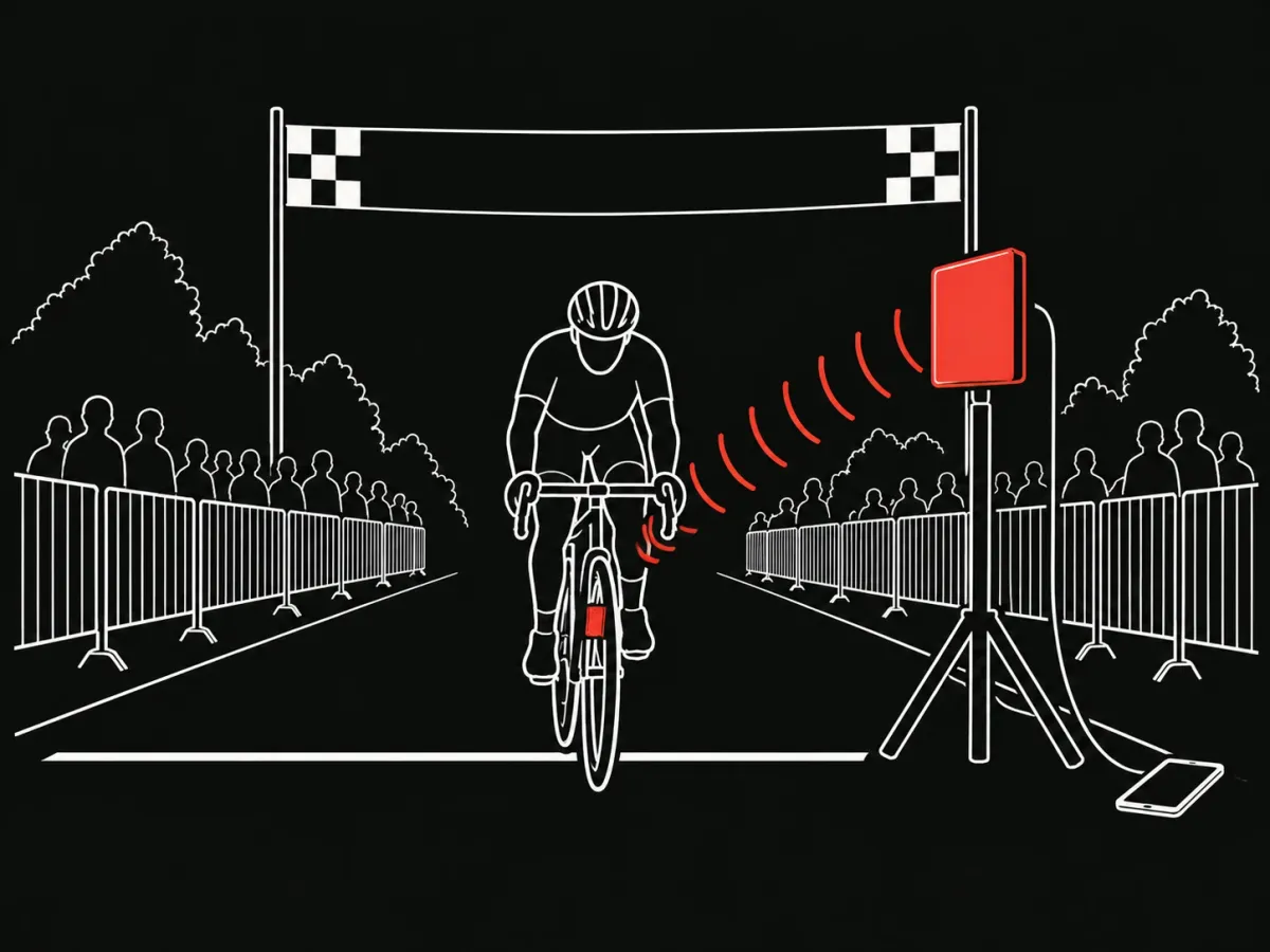 A cyclist crosses the finish while a UHF antenna on a stand beside the course reads the chip on the bike from a distance.